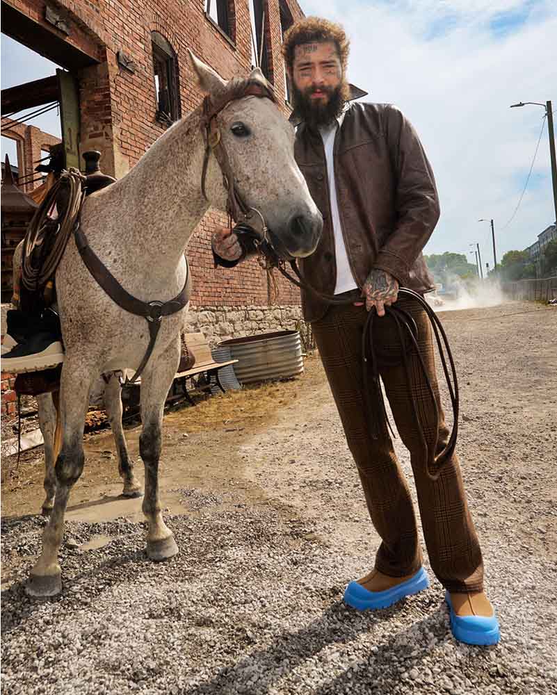 Post Malone se tient à côté d’un cheval et porte notre sabot Tasman Weather Hybrid.