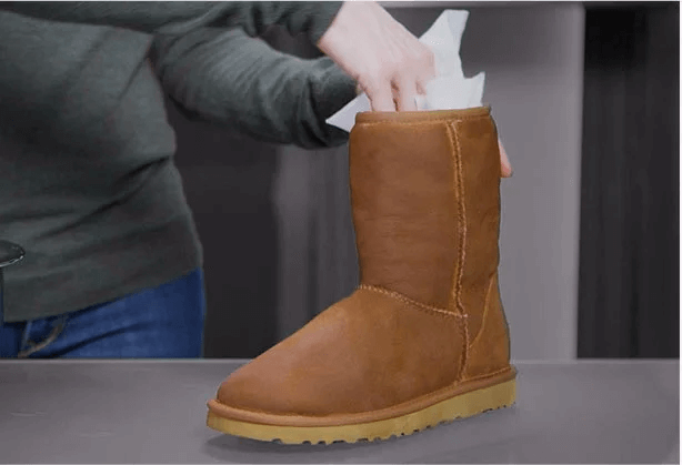 woman stuffing UGG classic with paper towels