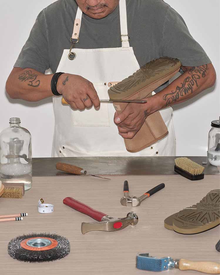 Worker restoring an UGG Classic boot with tools on a table.