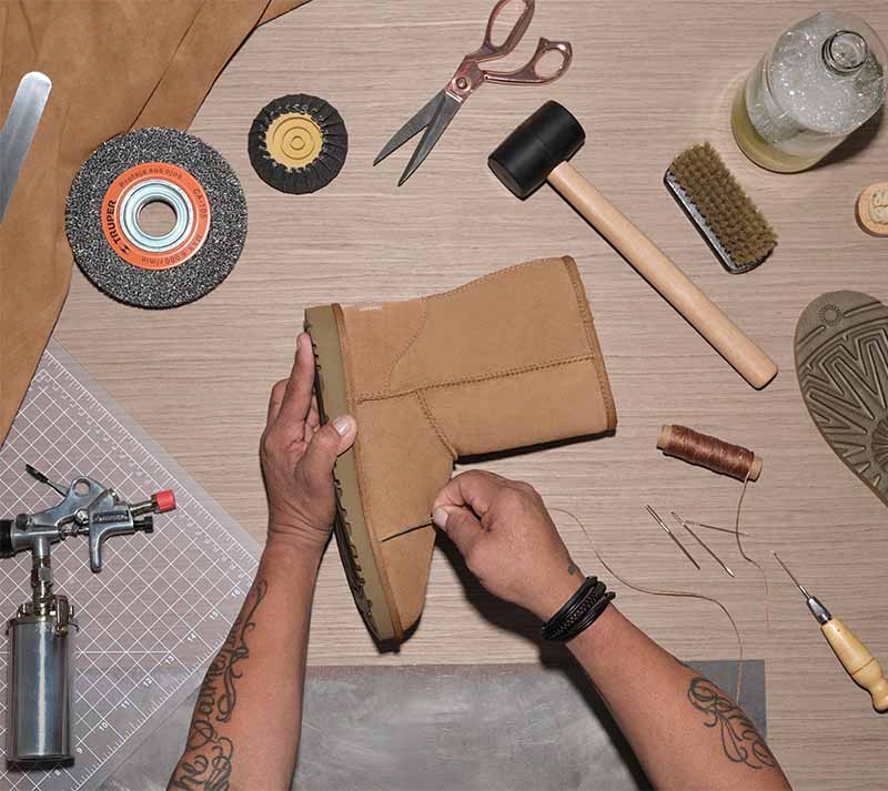 Worker renewing an UGG Classic boot with tools on a table.