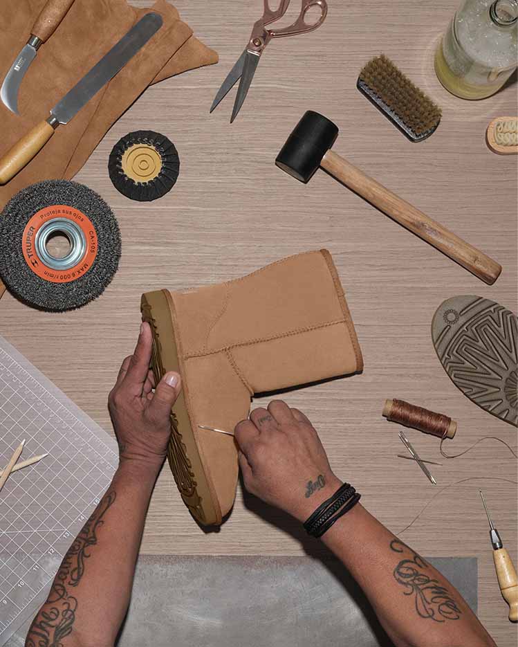 Worker renewing an UGG Classic boot with tools on a table.