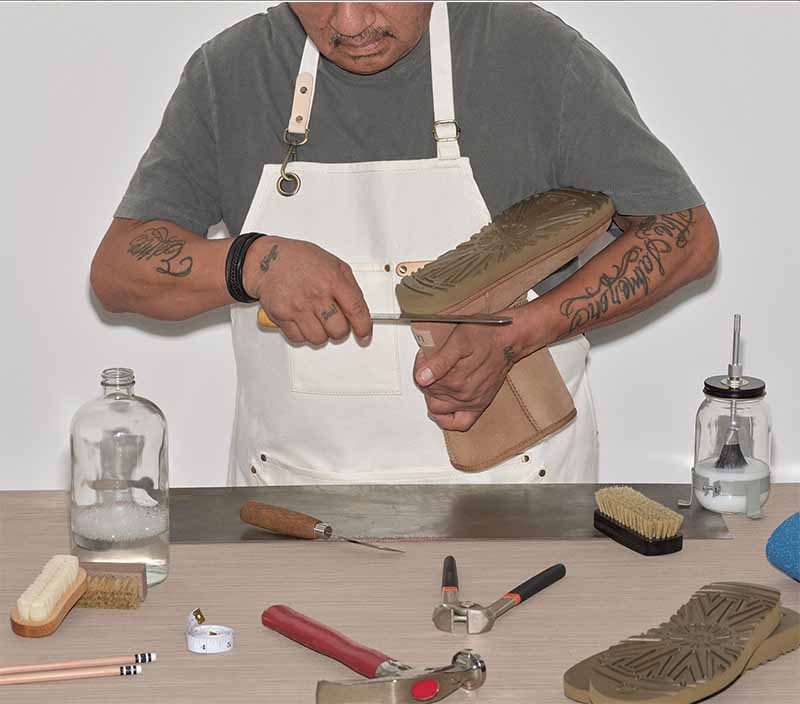 Worker restoring an UGG Classic boot with tools on a table.