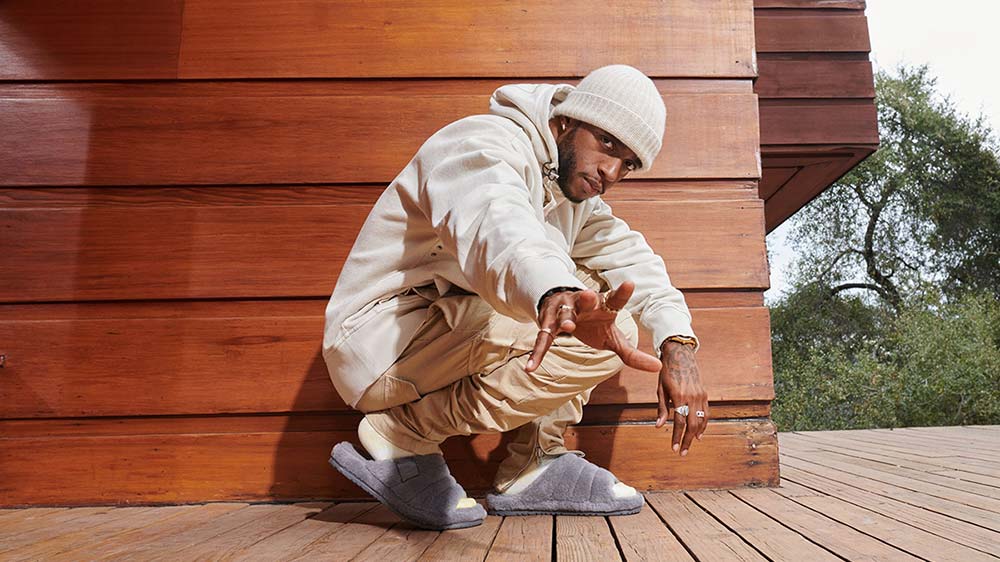 Man in UGG sandals holding hand out.