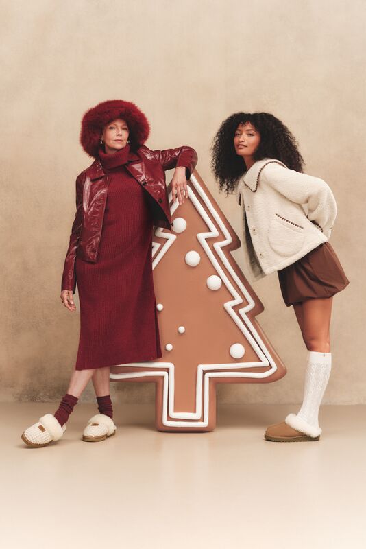 Two women wearing UGG Slippers close to a decorative Christmas tree.