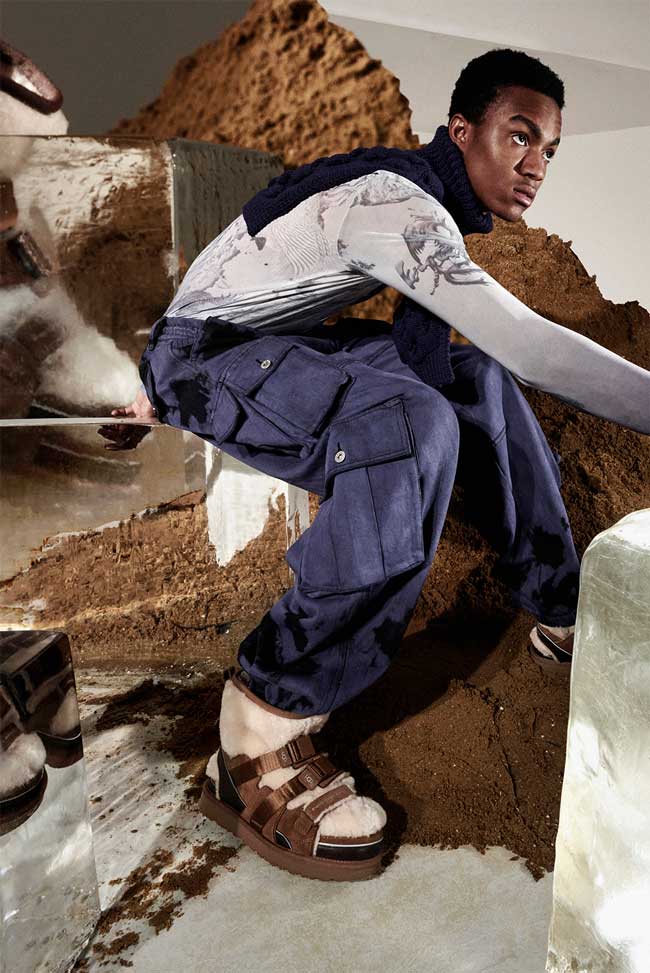 Model working, with a backdrop of dirt and block ice, wearing UGG boots by Feng Chen Wang.