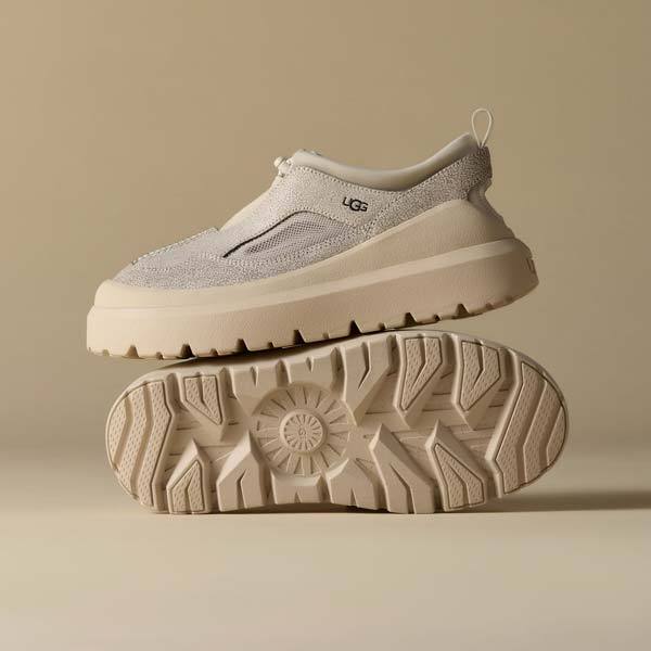 Une paire de chaussures UGG en cuir craquelé sur un fond beige.