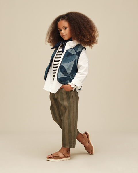 A kid wearing the UGG Goldenstar sandal and a fun, complimentary fit on a plain, bright backdrop.