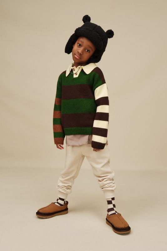 A kid wearing UGGs and a fun fit, complimented by an adorable, fuzzy, bear hat.