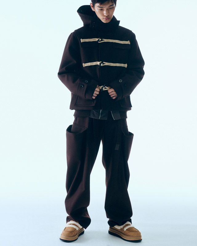 A masculine person wearing the new UGG sacai collaboration shoes, paired with a matching, well constructed fit.