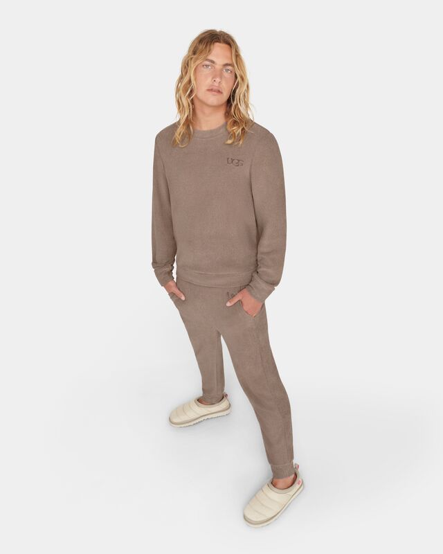 A shot of a man wearing the Coen long-sleeve shirt, the Brantley pant and the Tasman LTA slipper against a white background.