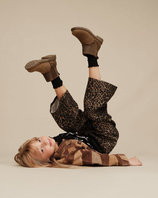 A kid in a fun and stylish fit playfully showing off their new UGG boots.