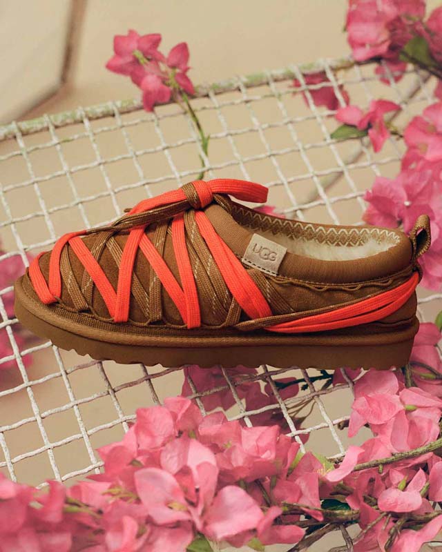 A Men's Tasman Lace in chestnut displayed on a white mesh with pink flowers against a tan background.