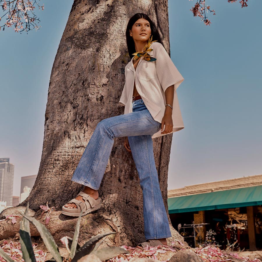 A lifestyle image of a woman stood near a tree, wearing the Goldenstar Hi Slide.