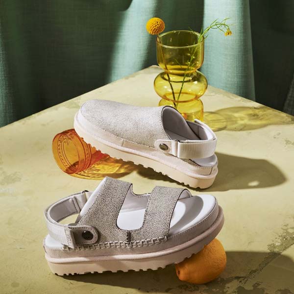 Une paire de chaussures UGG en cuir craquelé sur une table avec un citron et un verre.