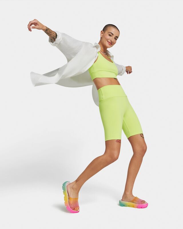 A shot of a woman posing with open arms wearing the Jella Clear Watercolors Slide against a white background.